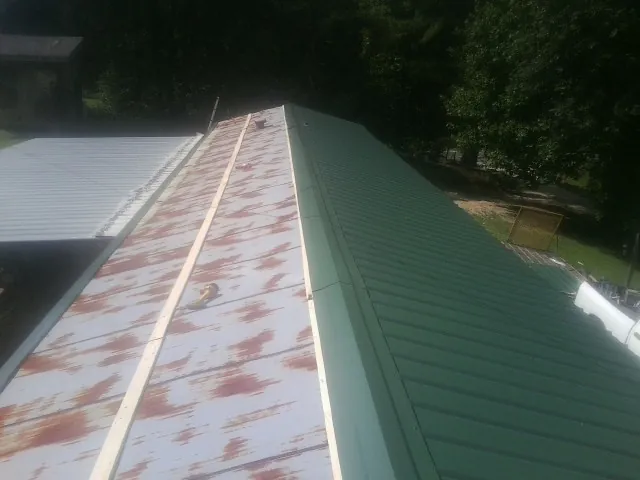 Old rusted panels beside newly installed green metal roofing — Wind Damage Roof Repair by Roofing Brothers in Grouse Creek