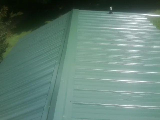 New green metal panels meeting at the ridge of a roof — Flat Roof Repair work by our crew in Grouse Creek