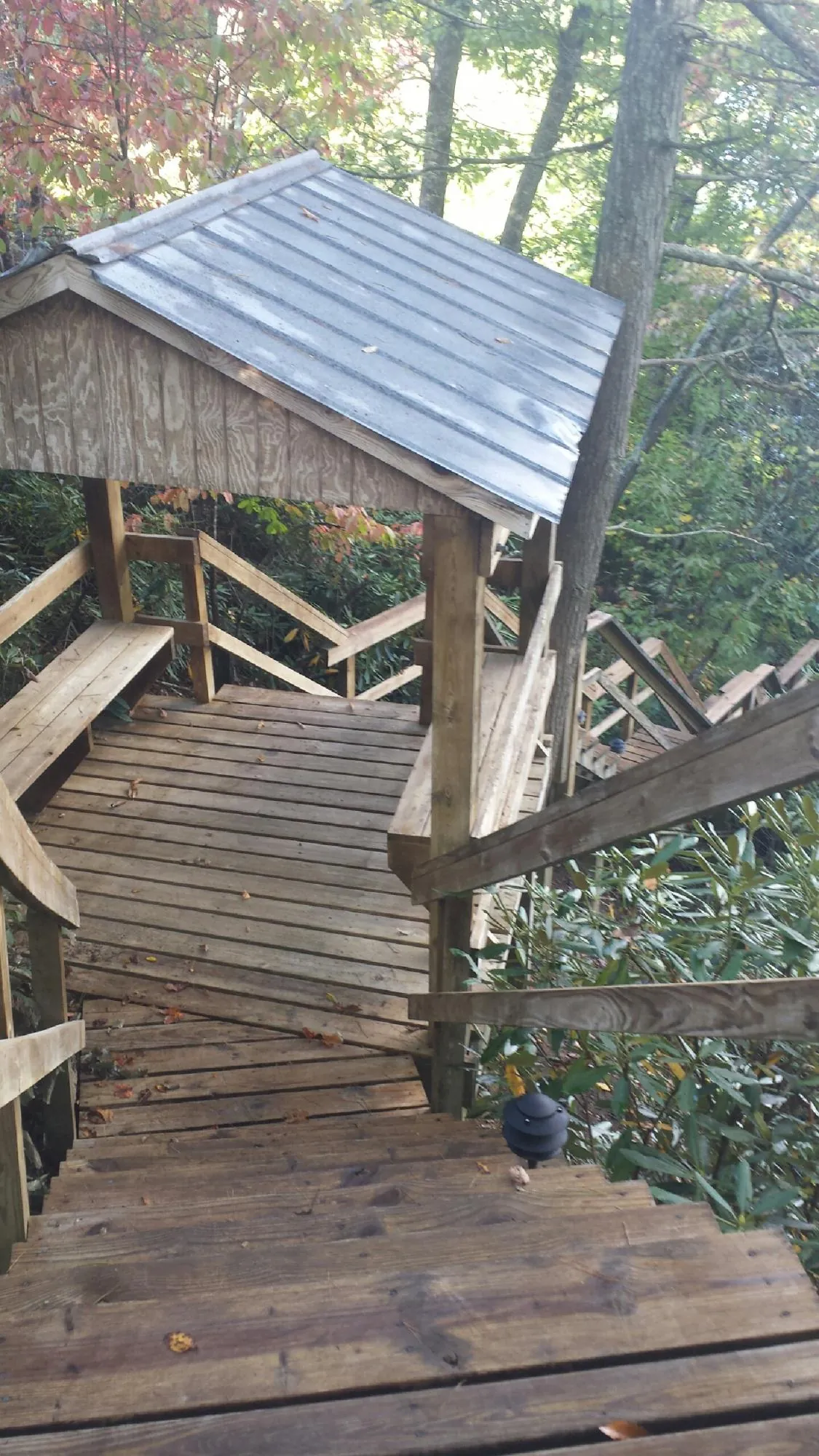 Metal roofed shelter over wooden steps on a wooded walkway — Skylight Repair & Installation work by our crew in Grouse Creek