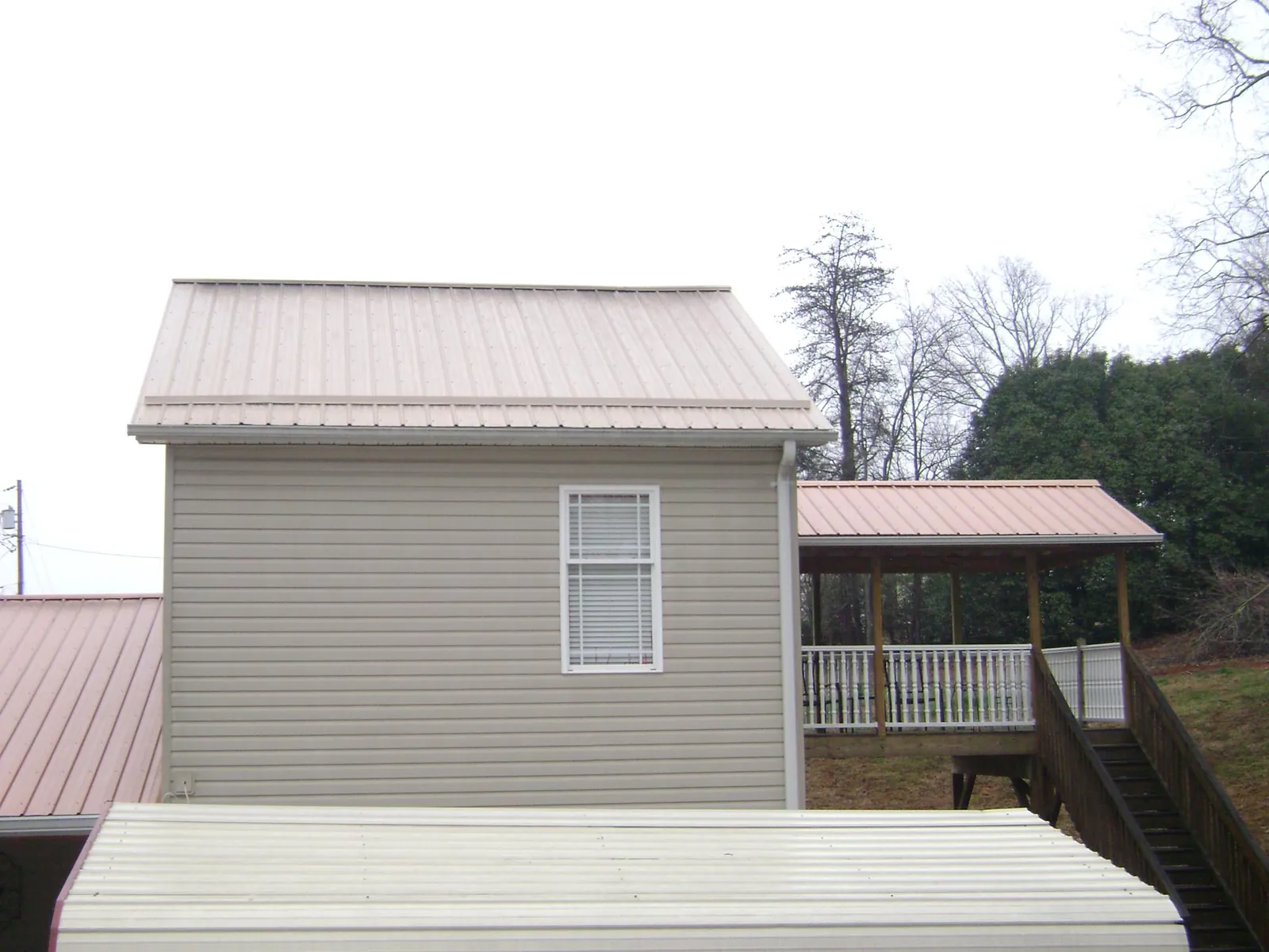 Tan metal roofs on a two story addition and attached porch, from a Roof Replacement job in Grouse Creek