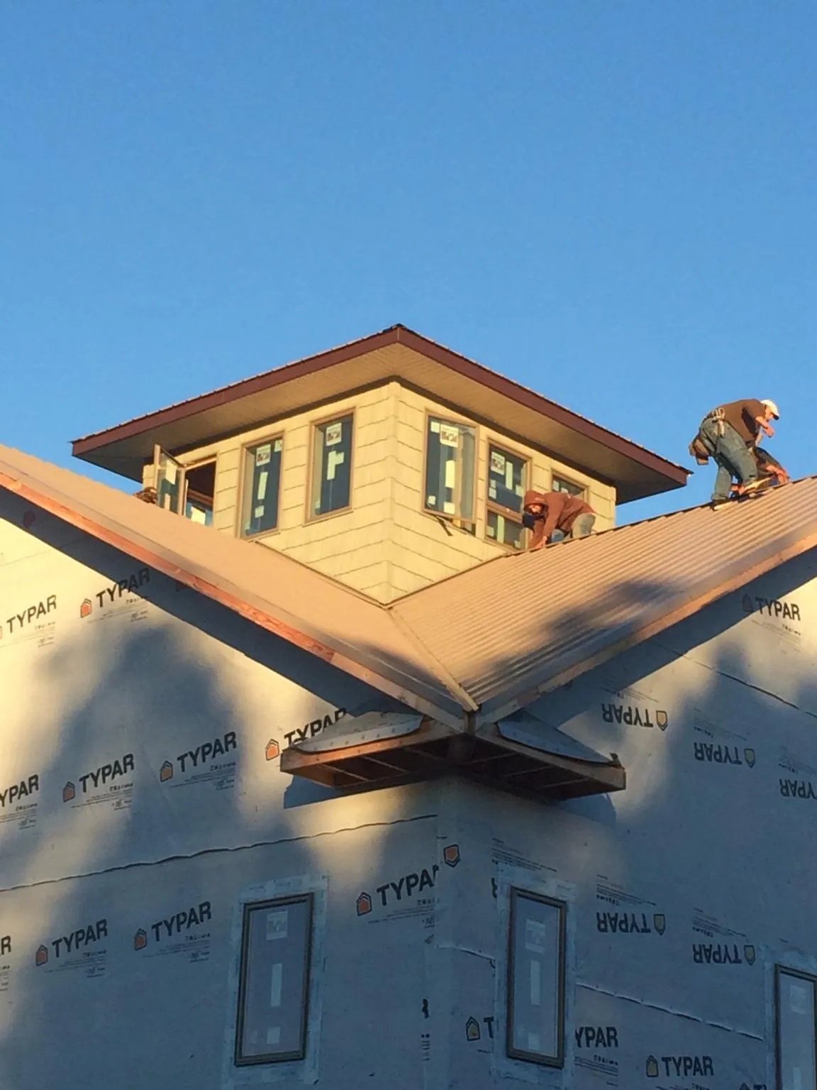 Roofers working around a rooftop cupola on a new metal roof at sunset — Roof Waterproofing in Grouse Creek by Roofing Brothers